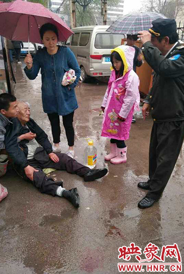 女孩為倒地老人撐傘。