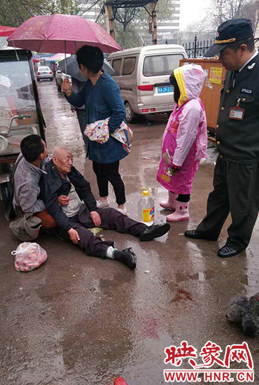 女孩為倒地老人撐傘。