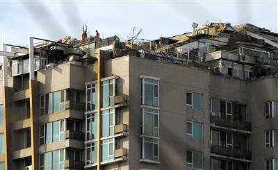 　　昨日，身穿橘黃色馬甲的工作人員在人濟山莊樓頂拆除違章建筑。新京報記者 吳江 攝