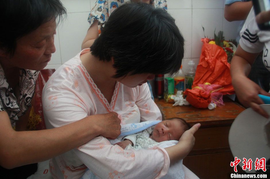 圖為久別重逢，獲救嬰兒母親悉心撫摸愛子。張一辰 攝