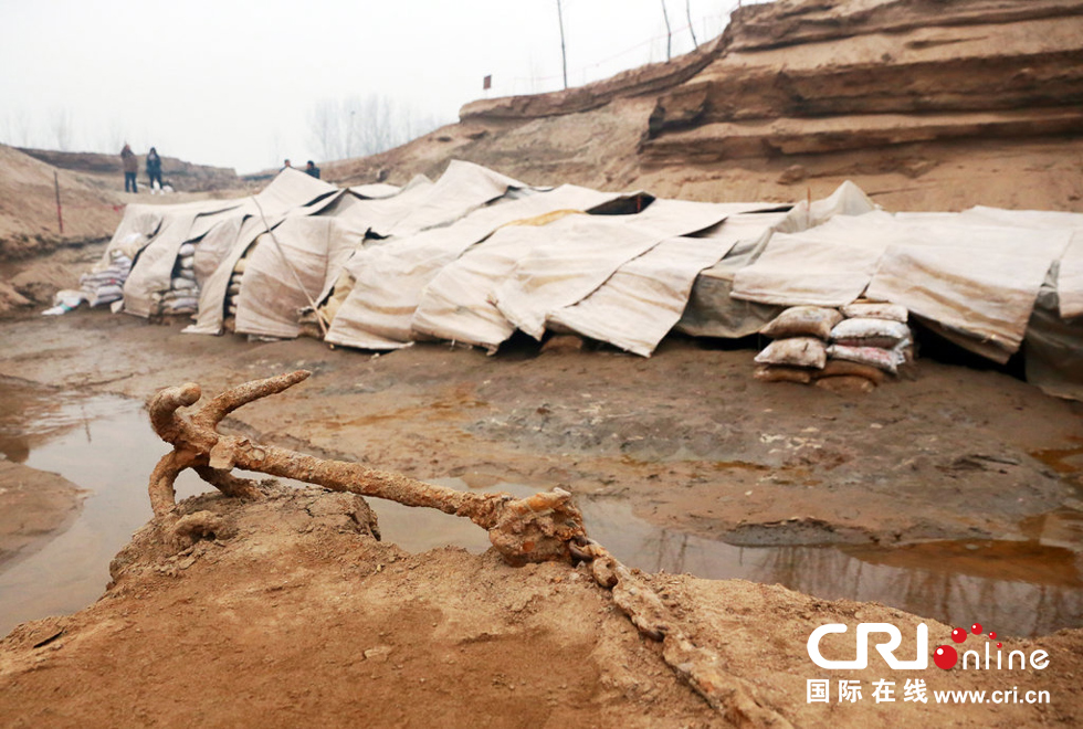 2014年1月6日，河南洛陽古沉船發(fā)掘現(xiàn)場，古沉船鐵錨從見天日，靜靜地躺在古船旁。