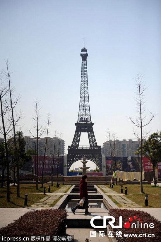 　2014年3月21日，杭州天都城，農(nóng)民在山寨埃菲爾鐵塔下耕作。圖片來源：東方IC