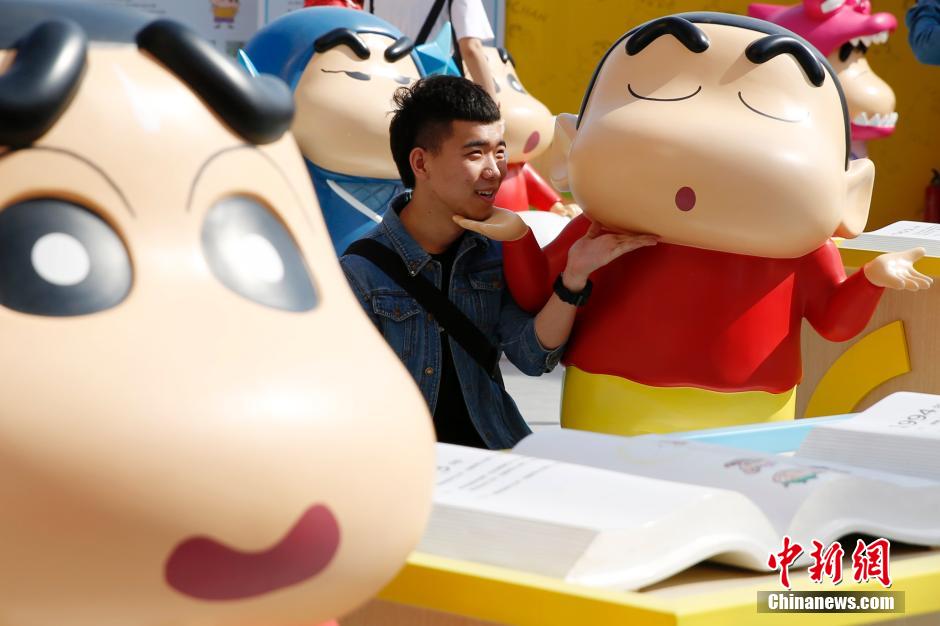 4月22日，游客與蠟筆小新合影。“蠟筆小新25周年紀(jì)念特展”日前在北京開展，吸引了不少市民游客。