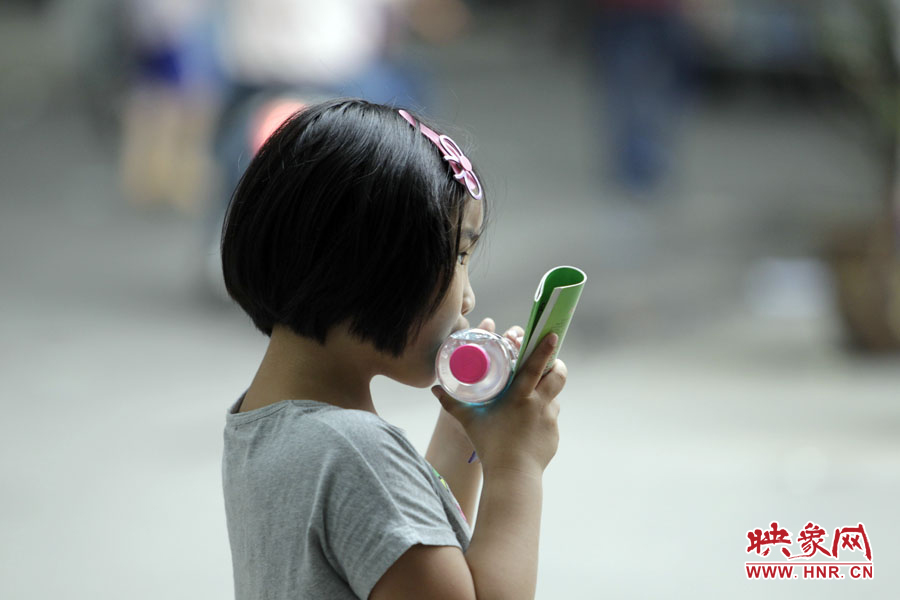 6月7日，鄭州回中考點，一名孩子拿著一瓶礦泉水，等待哥哥走出考場