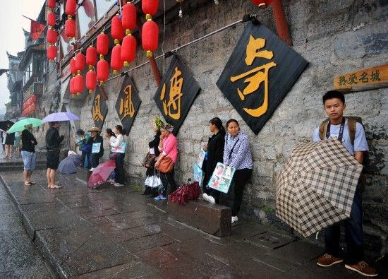 　4月29日上午11時(shí)20分，一些游客和古城當(dāng)?shù)氐木用穸阍谝粋€(gè)酒吧的屋檐下避雨。這些當(dāng)?shù)鼐用褚詾橛慰团恼罩\生，一場(chǎng)降雨讓他們的生意更加清淡。