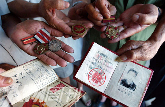 幾位志愿軍老兵展示自己的立功證、傷殘軍人證與勛章