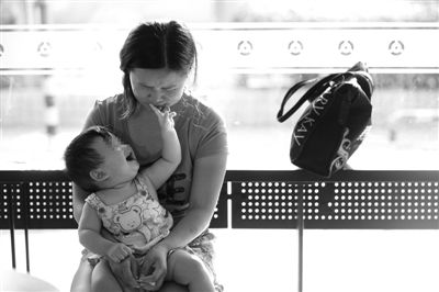 昨日，肯德基京廣中心店門口，姜女士提起跟養(yǎng)父母的關(guān)系時(shí)落淚，懷中9個(gè)月的女兒笑著跟她玩。新京報(bào)記者 薛珺 攝