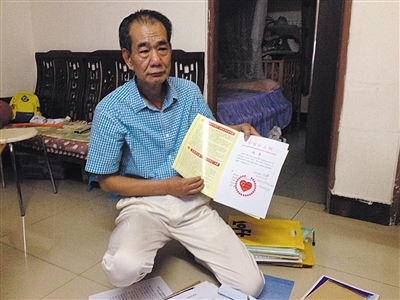 翻出一家網(wǎng)站贈予的“中國好人”證書，區(qū)少坤單膝跪在地上，“你看，我是中國好人啊?！?范春旭 攝