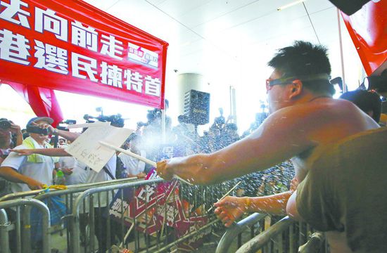 17日，在香港立法會外，一名反對政改的男子向支持派人群投擲標(biāo)牌。