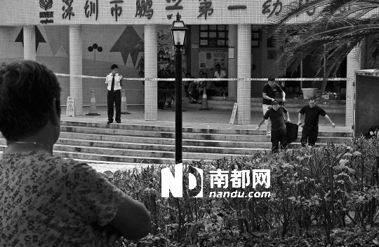→7月19日，鵬興花園第一幼兒園門(mén)前，民警在現(xiàn)場(chǎng)進(jìn)行完勘查取證后，園長(zhǎng)和保安的尸體被運(yùn)走。南都記者 徐文閣 攝