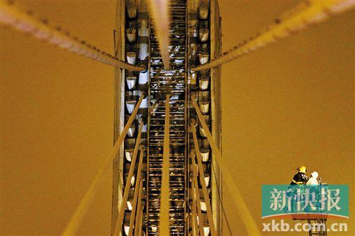 截至今日零時，男子仍未有下橋舉動。圖為公安和消防人員乘消防云梯在高空上和男子交談。