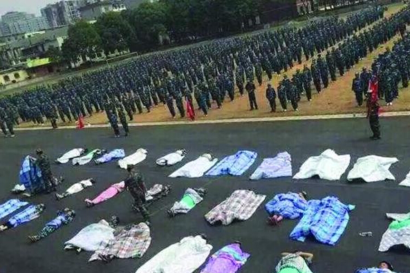 20多名女生躺在瀝青跑道上，身上嚴嚴實實地裹著棉被，接受太陽的照曬。
