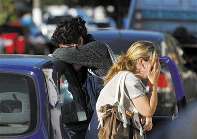 27日，遇難者親友在火災(zāi)現(xiàn)場旁哭泣。