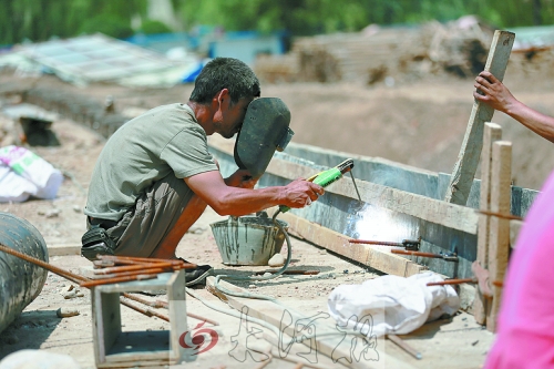 　正午陽(yáng)光下，工地上的焊接工人還在認(rèn)真工作。