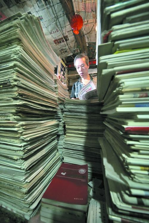 王曉民坐在寫字桌前，被報(bào)紙淹沒。
