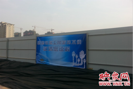 道路南側(cè)圍起了白色的圍擋，墻上標(biāo)示著“因地鐵施工帶來(lái)的不便敬請(qǐng)您諒解”的提示牌。