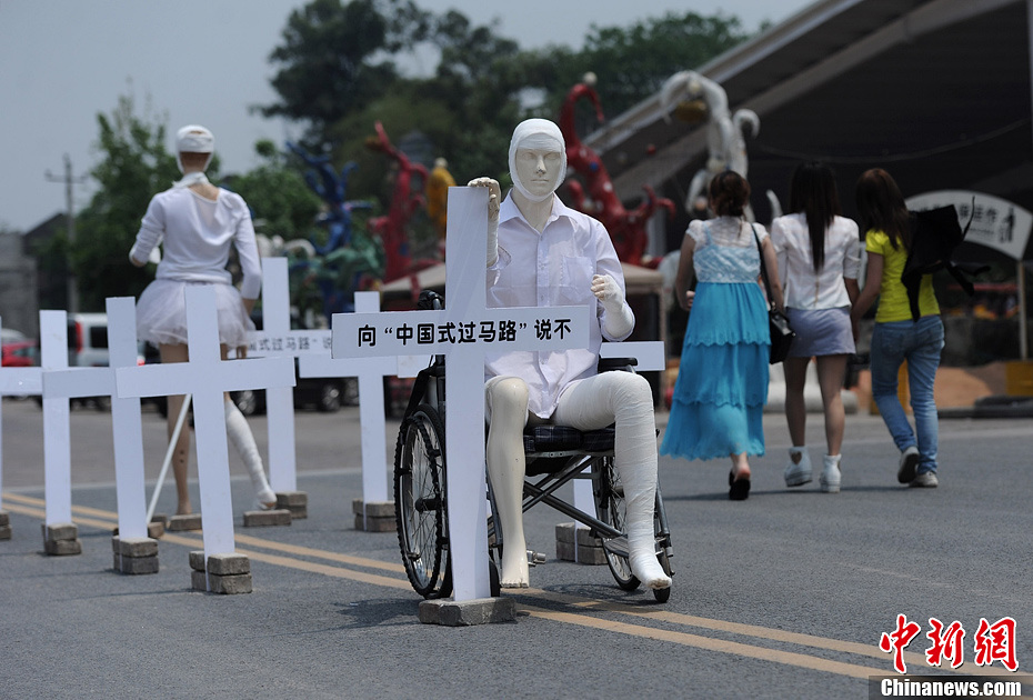 4月16日，重慶市洋人街上擺放著兩個(gè)受了傷的塑料人像“模特”，旁邊十字架上寫著向“中國式過馬路”說不