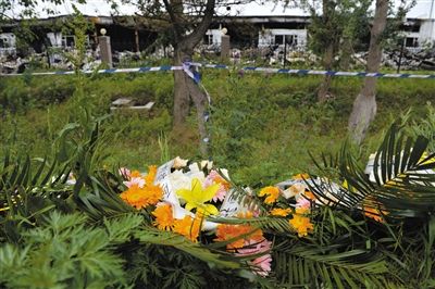 昨日，吉林省德惠市吉林寶源豐禽業(yè)有限公司燃燒事故現(xiàn)場(chǎng)警戒線外，遇難者家屬在路邊擺放了花圈祭奠逝去的親人。吳江 攝