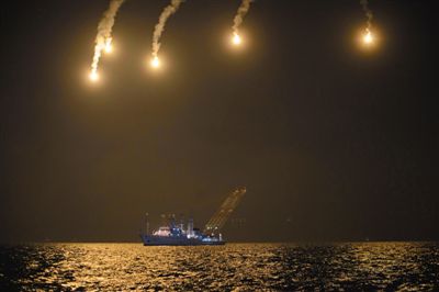 22日，搜救人員在照明彈的光亮下連夜搜救。