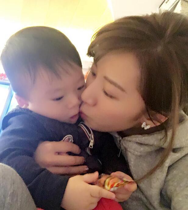 照片中李念狂吻兒子，小寶貝自顧自地玩著。