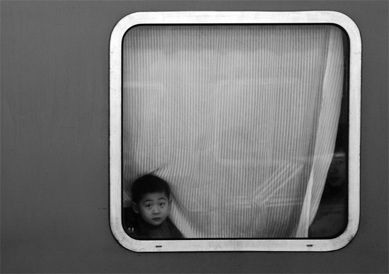 一個(gè)孩子把頭伸向窗外，他想再看送別的親人一眼