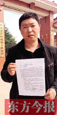 吳大強(qiáng)手持還款協(xié)議在鎮(zhèn)政府門(mén)前