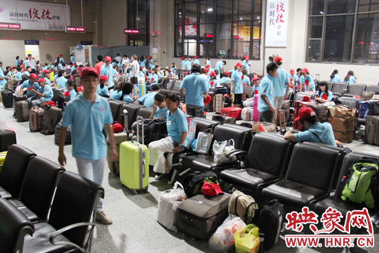 大學(xué)生志愿者在火車站候車室內(nèi)整裝待發(fā)。