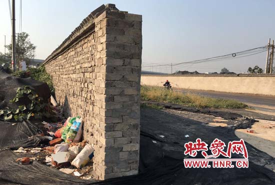 一墻之隔，一邊是道路，一邊是垃圾和荒草，市民質(zhì)疑其為遮羞墻。