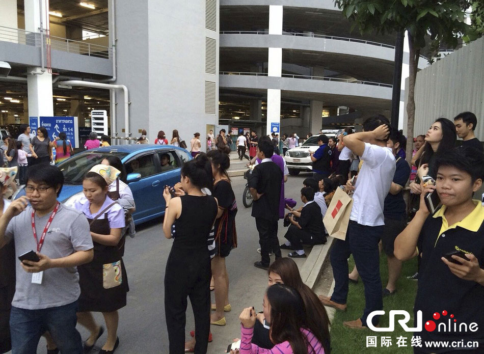 當?shù)貢r間2014年5月5日，泰國清萊，工人們站在一棟大樓外避難。