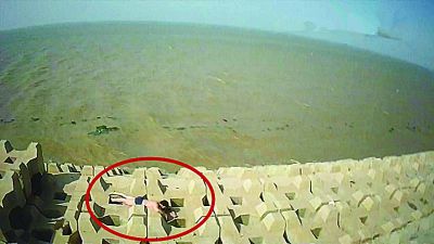 孫正龍游上岸，趴在海邊精疲力盡。