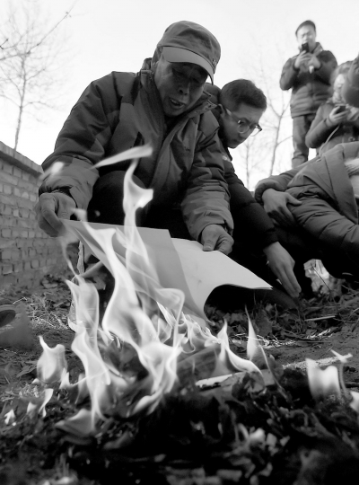 李三仁在兒子墳前焚燒再審無罪判決文書的復印件。新華社發(fā)