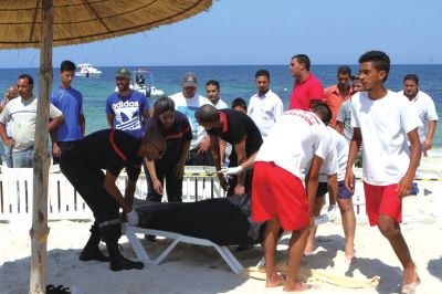 6月26日，在突尼斯蘇塞，救生員和醫(yī)務(wù)人員在發(fā)生襲擊事件的海灘運(yùn)送一名死者的遺體。新華社發(fā)