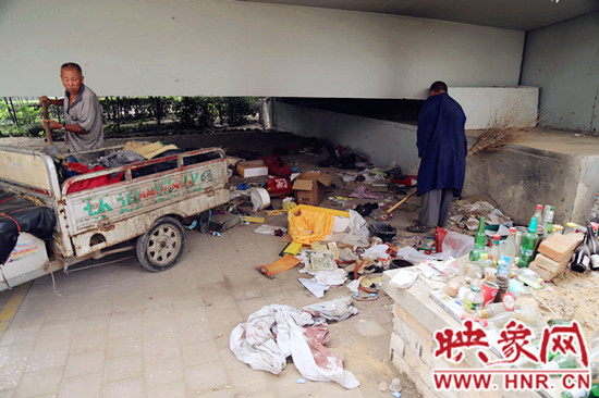 負(fù)責(zé)高架橋下綠化的人員在清理流浪漢留下的垃圾和雜物。