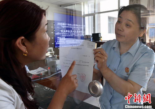 資料圖：2015年5月4日，河北石家莊市橋西區(qū)人民法院立案庭庭長齊燕正在為立案人辦理相關(guān)手續(xù)，完成整個(gè)過程只用了5分鐘。當(dāng)日是立案登記制改革首個(gè)工作日，該院共立案36件，立案率達(dá)到90%。中新社發(fā) 翟羽佳 攝