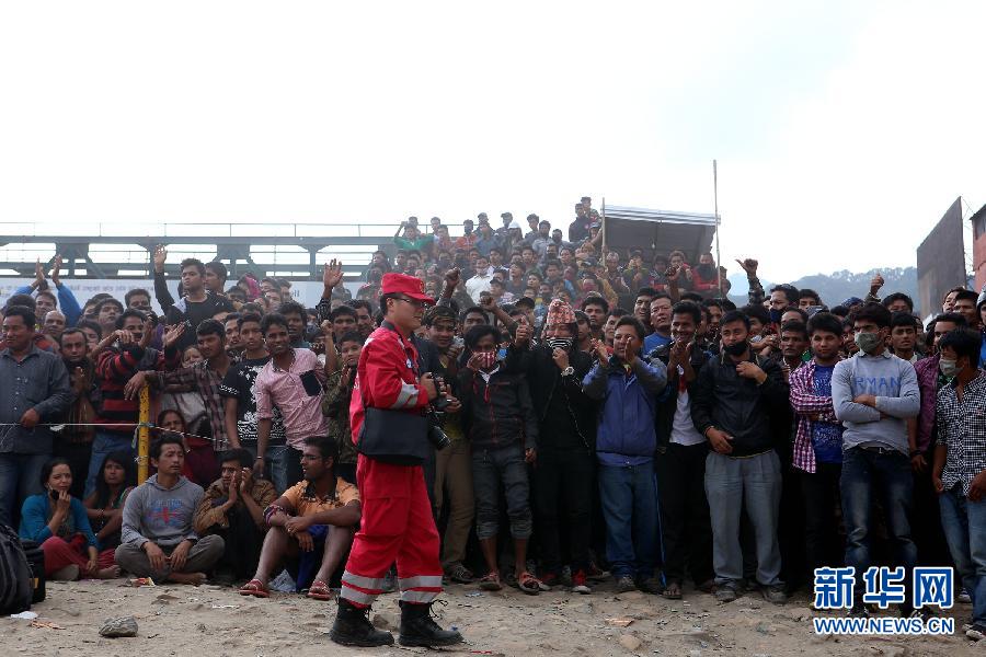 圍觀的尼泊爾民眾在中國國際救援隊成功搜救出幸存者后向搜救隊員歡呼致意。