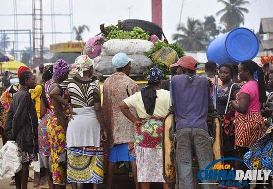 當(dāng)?shù)貢r(shí)間2014年8月14日，利比里亞蒙羅維亞，市場(chǎng)里的商人們圍著一輛汽車(chē)。