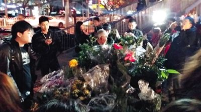 昨晚7時許，三里屯太古里西邊附近一過街天橋旁邊，聞訊而至的網(wǎng)友圍住了賣花老人，爭相買花。 網(wǎng)友“行者橙子”供圖