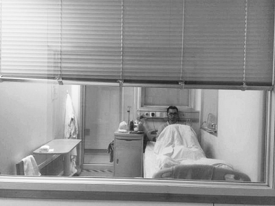 楊杰在醫(yī)院隔離病房中，沖記者揮了揮手。